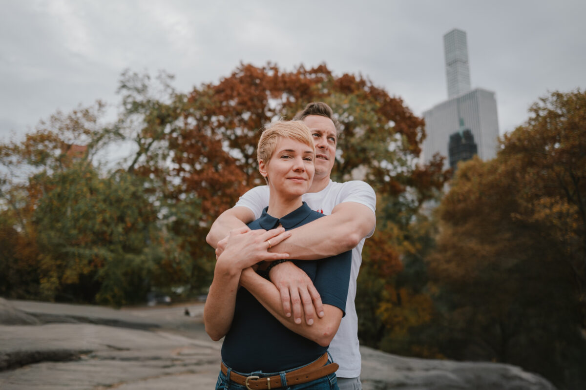 Fall engagement photos in Central Park, he hugs her from behind