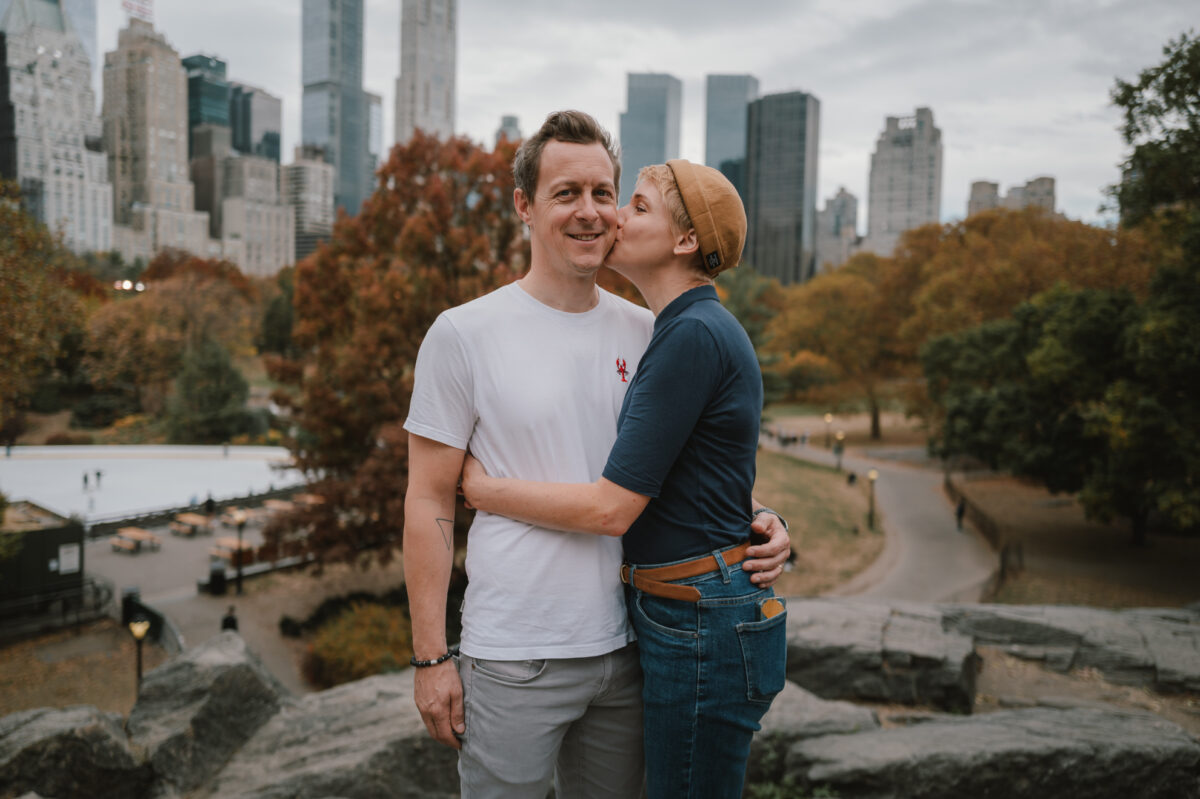 She kisses him on the cheek during their Central Park engagement photos